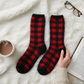 Mellow Monkey red and black buffalo plaid crew socks from the 1902 Collection on a cozy white faux fur background.