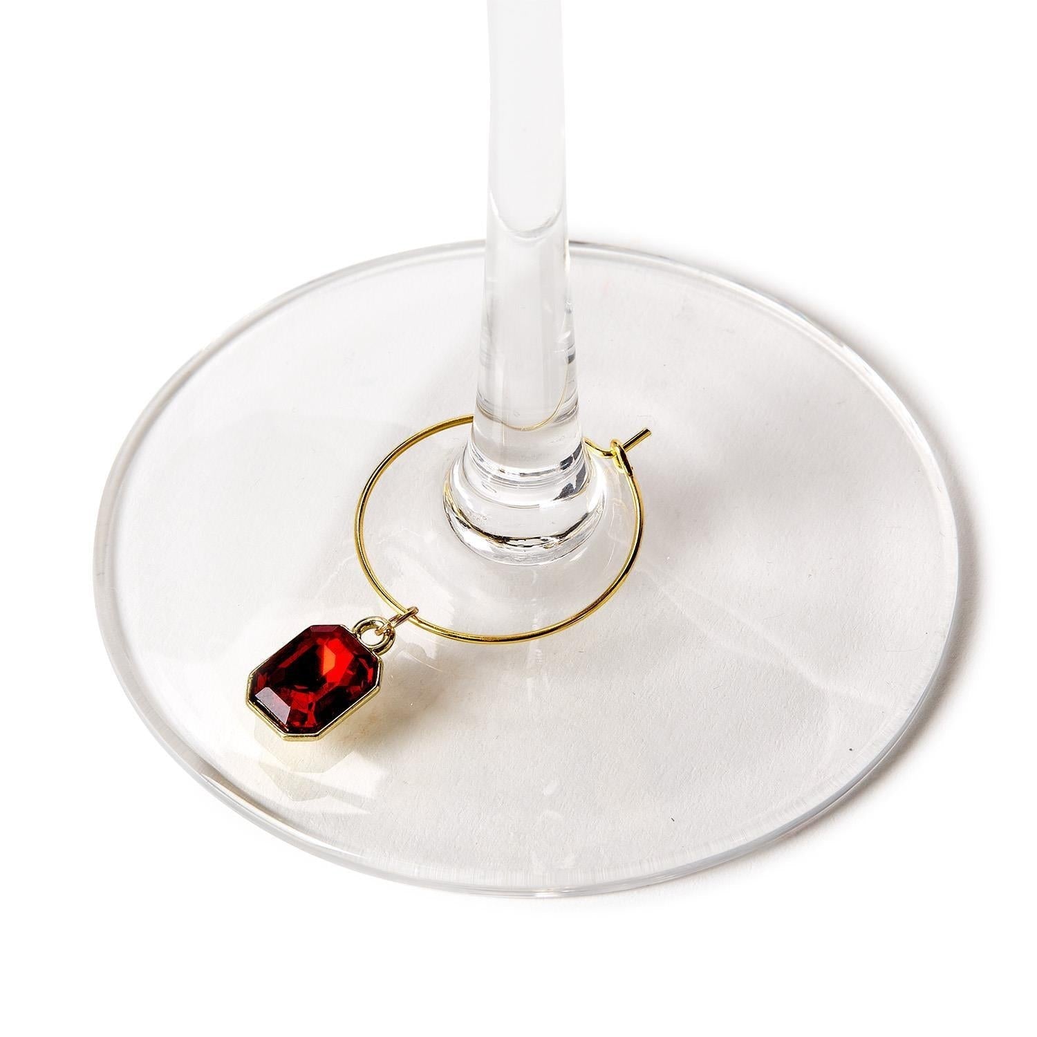 Mellow Monkey red gem wine glass charm attached to the stem of a clear glass base on a white background