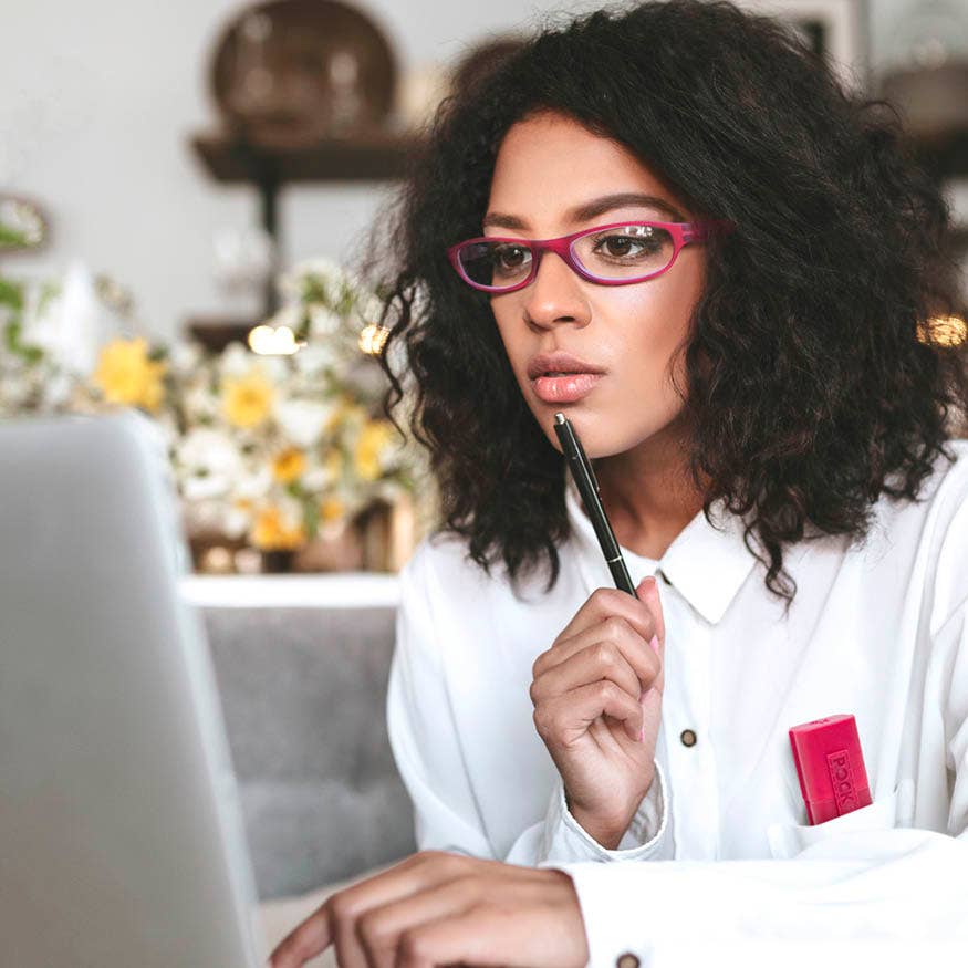 Mellow Monkey red pocket reading glasses worn by a woman working on a laptop with a matching case in her pocket