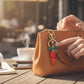 Mellow Monkey red and orange rhinestone carrot keychain with green leaf detail attached to a tan leather handbag.