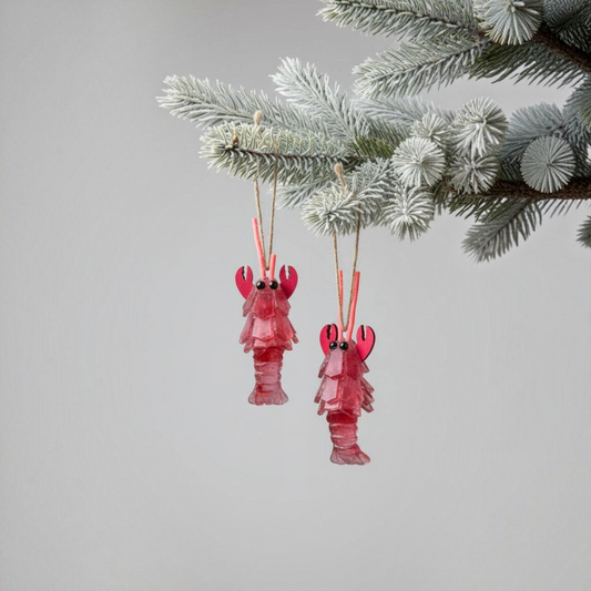 Mellow Monkey red sea glass lobster ornaments hanging on a frosted Christmas tree branch