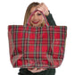 A woman holding a Mellow Monkey red tartan plaid nylon tote bag with a glossy PVC finish for holiday shopping.