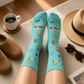Mellow Monkey light blue retirement socks featuring icons of sunglasses, hats, and books on a cozy floor setting