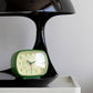 Mellow Monkey Kikkerland retro green desk alarm clock with a glow in the dark face sitting on a black surface