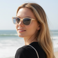 Woman wearing Mellow Monkey Riviera translucent reading sunglasses on a sunny beach