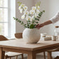 Mellow Monkey round white capiz shell vase filled with white orchids on a wooden dining table