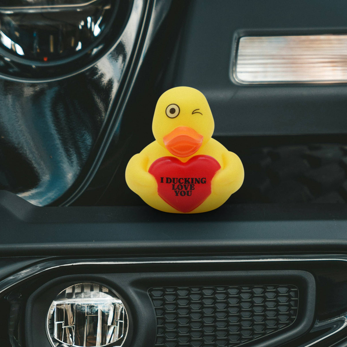 Mellow Monkey yellow rubber duck with a winking eye holding a red heart that says I Ducking Love You on a car bumper