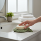 Mellow Monkey sage green fish-shaped bioplastic soap lift holding a round bar of soap on a bathroom vanity
