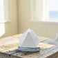 Mellow Monkey stoneware sailboat napkin holder with blue and white stripes on a rustic wooden table