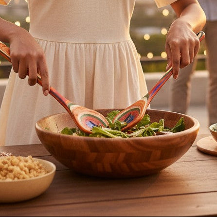 Mellow Monkey Marrakesh Collection salad serving utensil set, made of layered birch with vibrant colors, used by a woman tossing salad at a rooftop party.