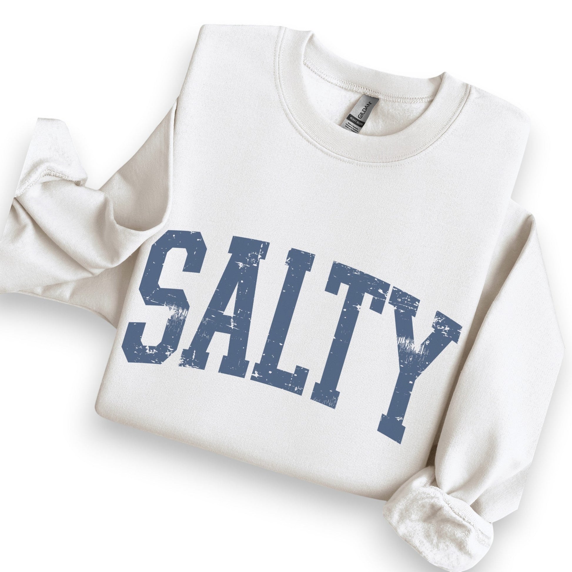 Mellow Monkey sand-colored crewneck sweatshirt with a distressed blue SALTY graphic, styled with casual accessories.
