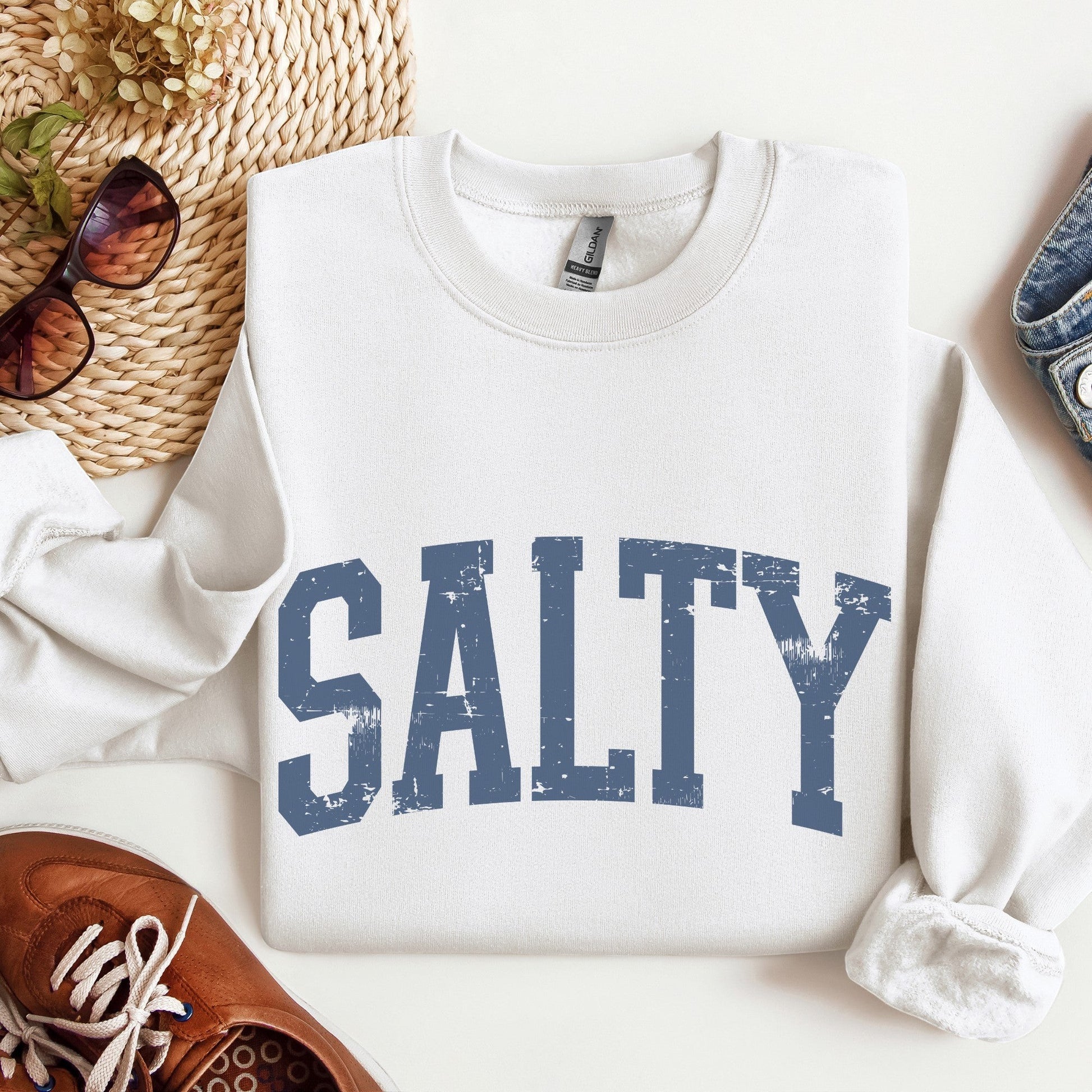 Mellow Monkey sand-colored crewneck sweatshirt featuring a distressed blue SALTY graphic, styled with casual accessories