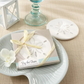 Mellow Monkey sand dollar stone coaster in a gift box with raffia ribbon, perfect for coastal wedding favors.