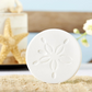 Mellow Monkey white sand dollar stone coaster with embossed coastal detail on a textured beach-themed surface.