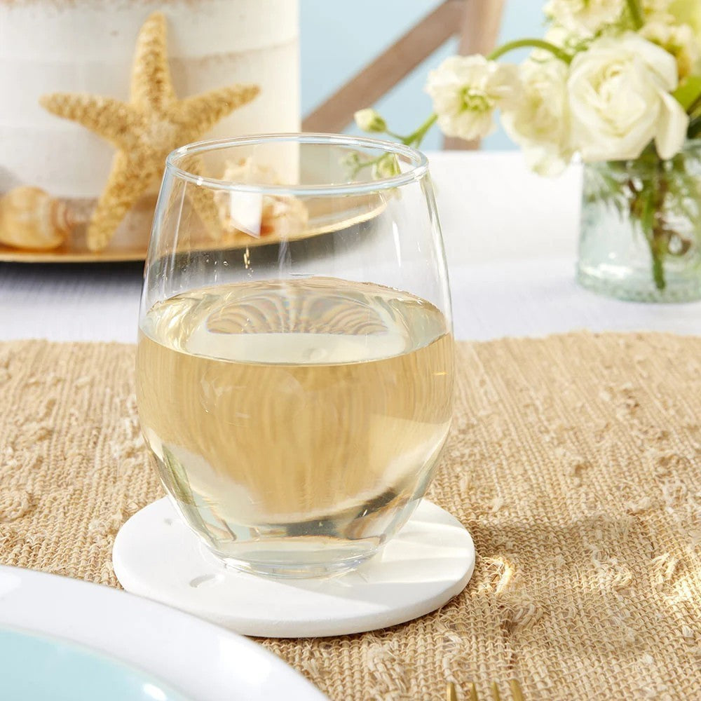 Mellow Monkey sand dollar stone coaster under a stemless wine glass on a textured table setting