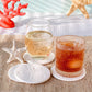 Mellow Monkey set of four white sandstone coasters with sand dollar designs on a beach-themed table setting.