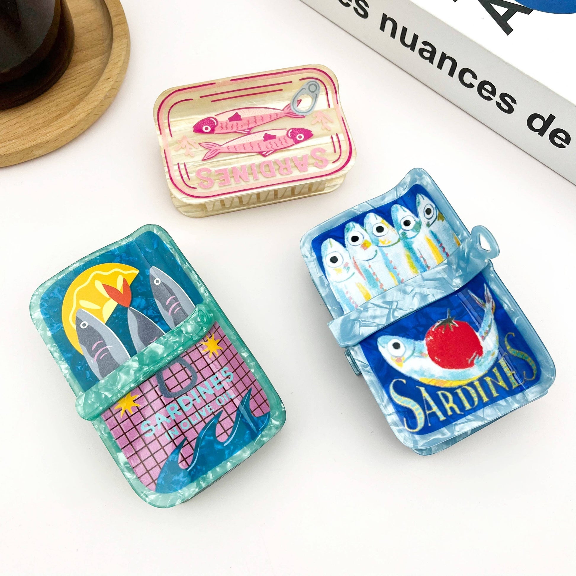 Mellow Monkey sardine can hair claw clips in three colorful, quirky designs with fish and tomato illustrations.