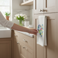 Mellow Monkey white cotton flour sack towel with a multicolor sea glass heart design hanging in a modern kitchen.