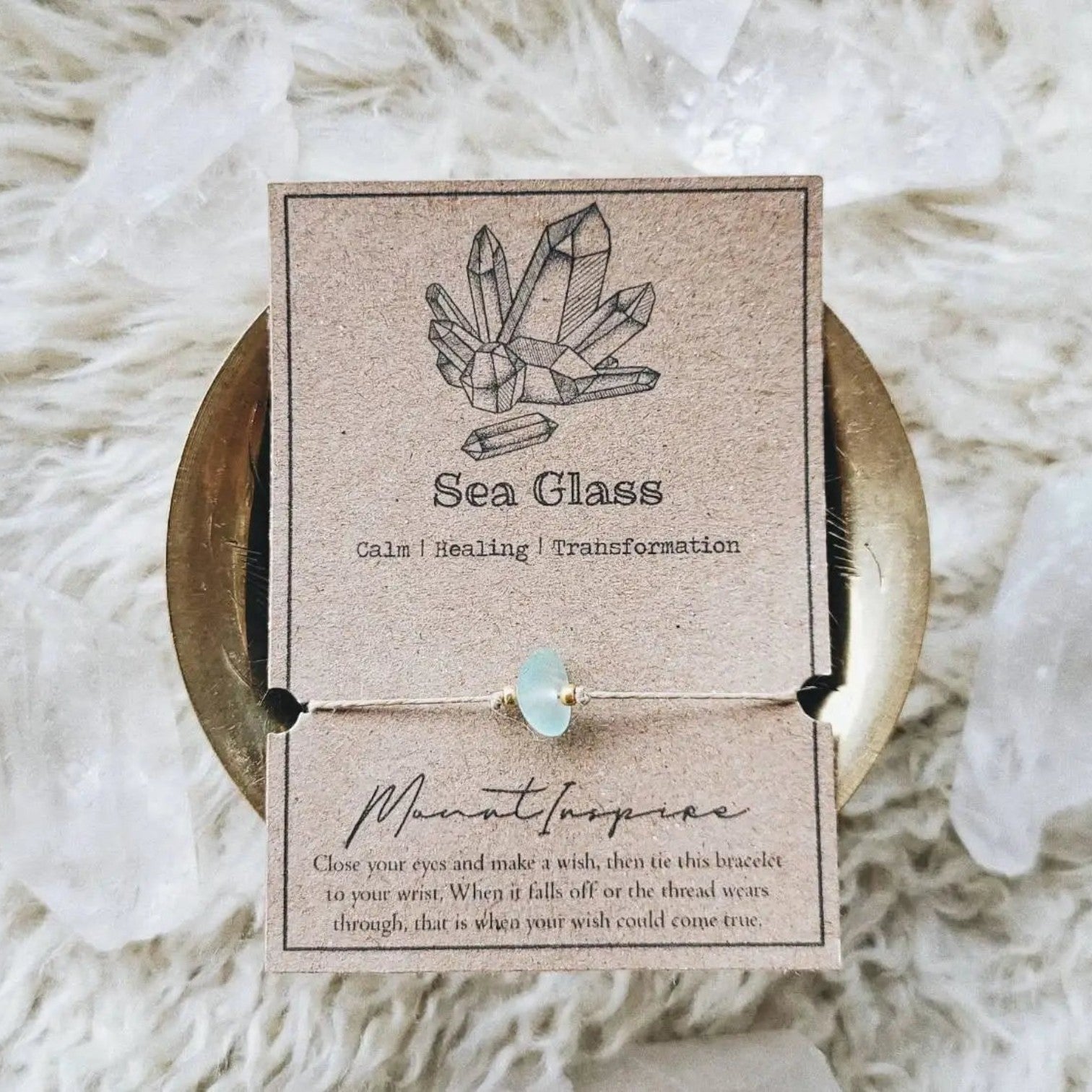 Mellow Monkey Sea Glass crystal wish bracelet on tan hemp cord with gold beads, displayed on a kraft paper card.