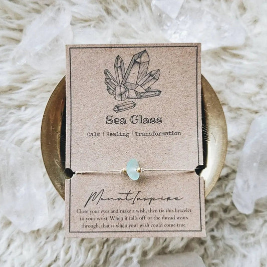 Mellow Monkey Sea Glass crystal wish bracelet on tan hemp cord with gold beads, displayed on a kraft paper card.