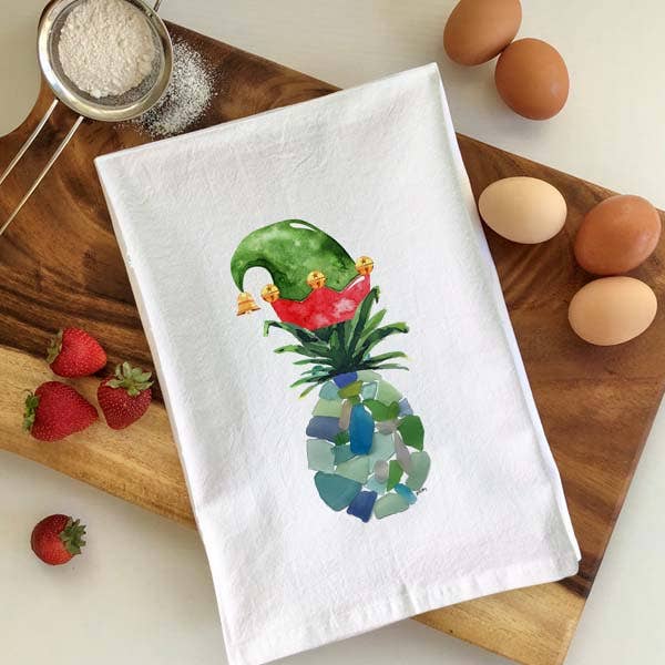 Mellow Monkey white cotton flour sack towel featuring a festive sea glass pineapple wearing a green and red elf hat.