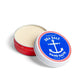 Mellow Monkey Swedish Dream Sea Salt hand salve in a round red metal tin with a blue and white anchor lid design.