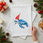 Mellow Monkey white cotton flour sack towel featuring a blue sea turtle wearing a red Santa hat on a festive table
