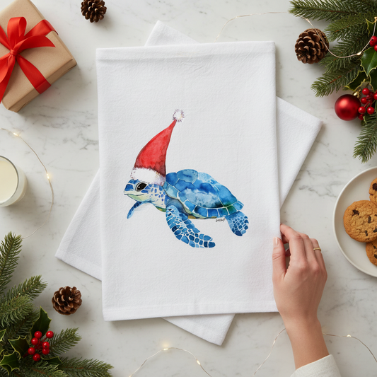 Mellow Monkey white cotton flour sack towel featuring a blue sea turtle wearing a red Santa hat on a festive table