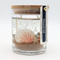 Mellow Monkey Sea Shell Beach Treasure gel candle with seashells, sand, and a wooden lid in a glass jar.