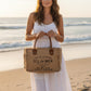 Mellow Monkey Sel De Mer canvas and leather crossbody bag with frayed edges held by a woman on a sandy beach.
