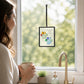 Mellow Monkey Sharon Nowlan suncatcher featuring a colorful pebble paw print design hanging in a bright window.