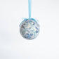 Mellow Monkey Kim Hovell shell trio decoupage ornament with blue ribbon hanging against a white background