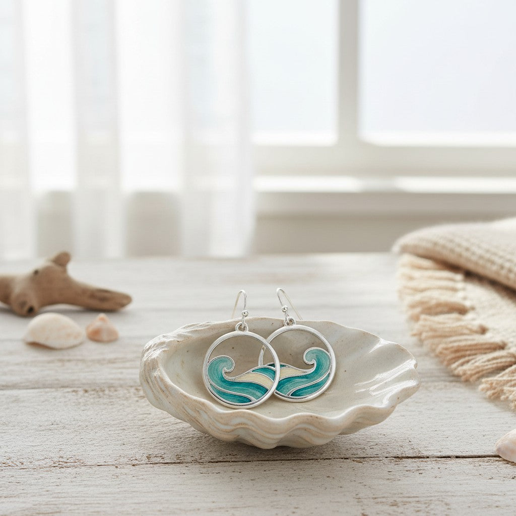 Mellow Monkey silver wave earrings with aqua enamel in a decorative shell dish on a rustic wooden table.