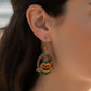 Mellow Monkey Silver Forest jack-o'-lantern hoop earrings with surgical steel wire worn by a woman at the beach.