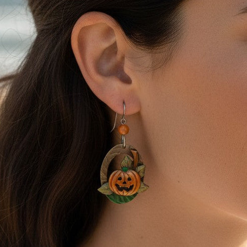 Mellow Monkey Silver Forest jack-o'-lantern hoop earrings with surgical steel wire worn by a woman at the beach.