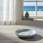 Mellow Monkey silver anklet with white scallop shell and blue bead, displayed on a ceramic dish by the ocean.