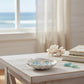 Mellow Monkey silver wave earrings with blue inlay displayed in a shell dish on a wooden table near the ocean.