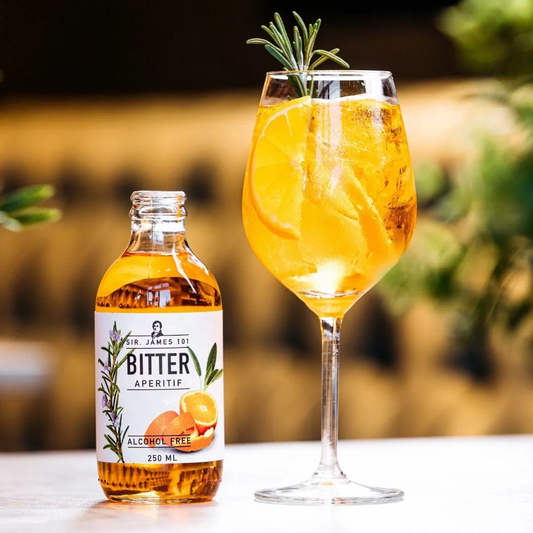 Mellow Monkey Sir. James 101 alcohol-free bitter aperitif spritz bottle next to a glass garnished with orange and herb