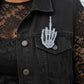 Mellow Monkey skeleton middle finger enamel pin with glow-in-the-dark effect pinned to a black denim vest.