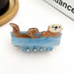 Mellow Monkey blue sleeping otter hair claw clip with a cute brown otter resting in water