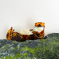 Mellow Monkey brown tortoiseshell sleeping otter hair claw clip resting on a mossy rock
