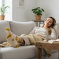 Mellow Monkey funny sloth socks in cream and yellow worn by a woman relaxing on a sofa with a coffee and book