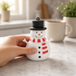 Mellow Monkey Chilly the Snowman squishy toy with a black top hat and red striped scarf held on a marble countertop.