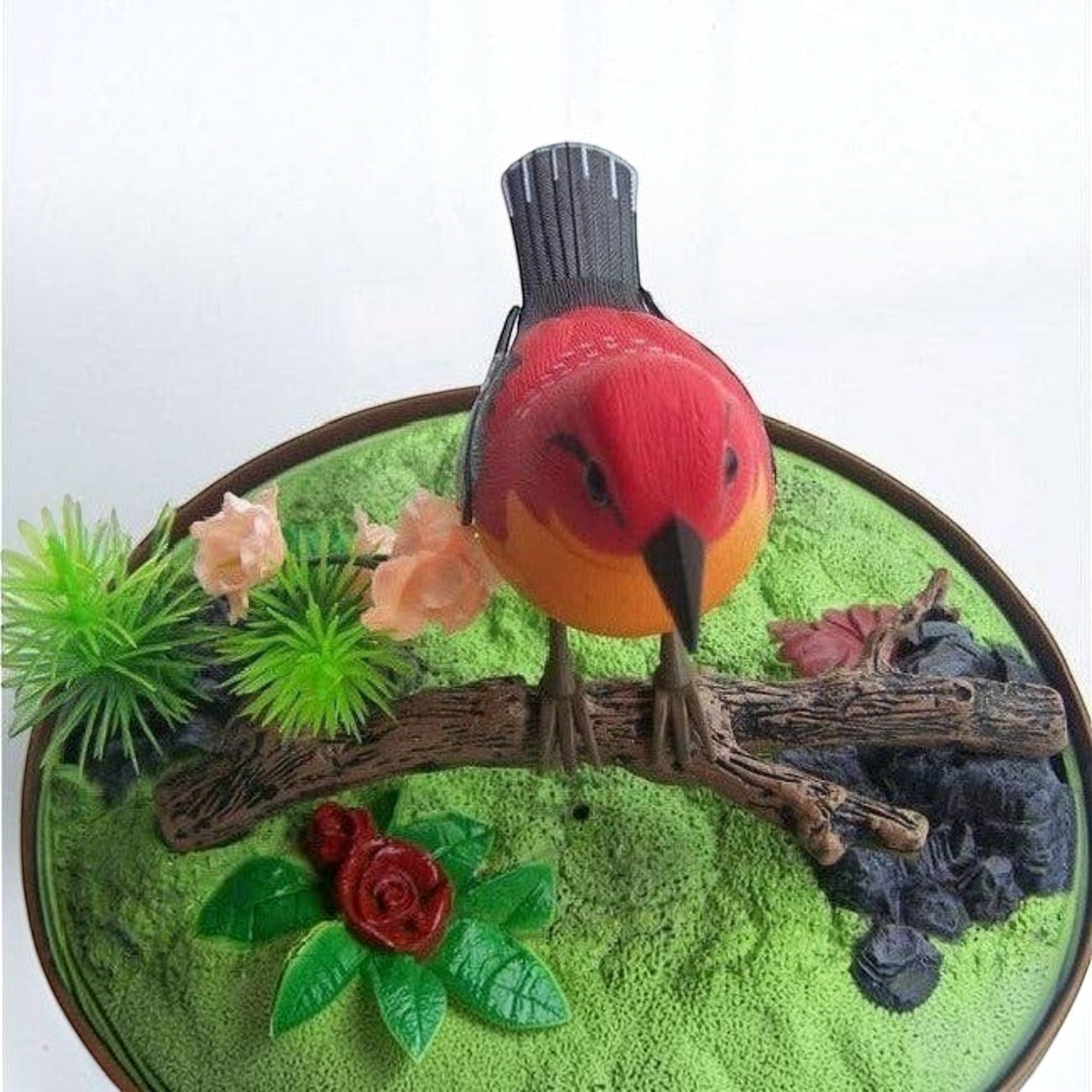 Mellow Monkey sound-activated red singing bird toy perched on a branch inside a decorative cage with faux greenery.
