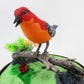 Mellow Monkey sound-activated red and orange toy bird on a branch inside a decorative cage