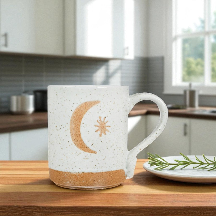 Mellow Monkey speckled stoneware mug featuring a hand-carved moon and star design on a kitchen counter.