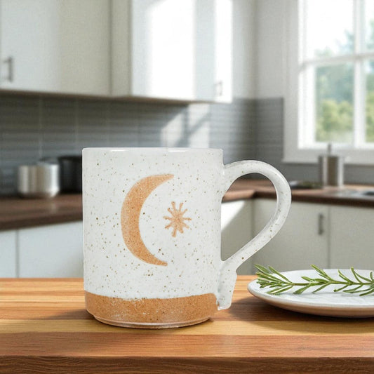Mellow Monkey speckled stoneware mug featuring a hand-carved moon and star design on a kitchen counter.