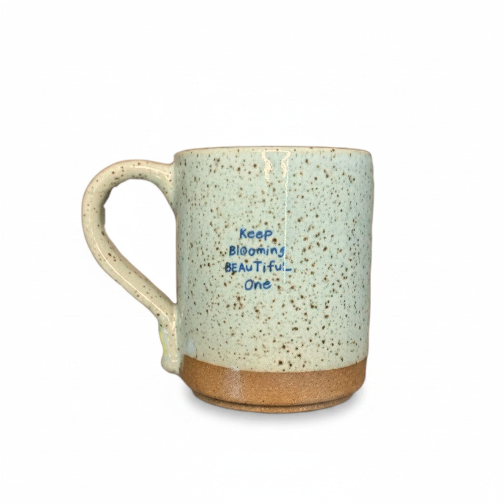 Mellow Monkey speckled stoneware mug with a hand-carved Keep Blooming Beautiful One quote in blue lettering