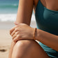 Mellow Monkey spice-colored seed bead bracelet with 18K gold plated accents worn by a woman on a sunny beach.