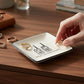 Mellow Monkey square ceramic trinket tray with walkie-talkie graphic and What The Fuck Over text on wooden desk